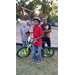 A young boy poses with his new bike with 2 little boys standing behind him
