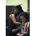 A man wearing a cap and gown embracing a young woman with a man smiling next to them