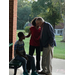 a young boy sits on a bench while a woman whispers into a mans ear
