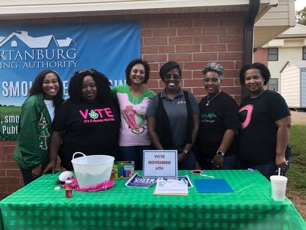 6 ladies standing in front of a table with Vote November 6th signs